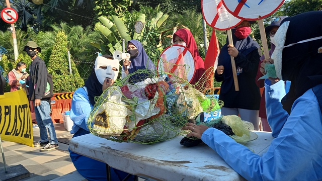 Aktivis Lingkungan Gelar Aksi Teatrikal Makan Plastik di Depan Grahadi